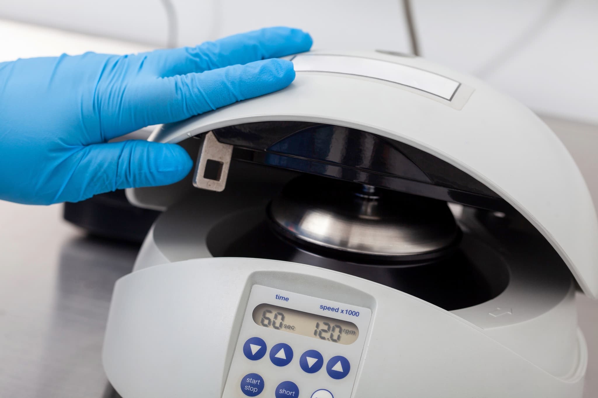 Gloved hand closing a benchtop centrifuge