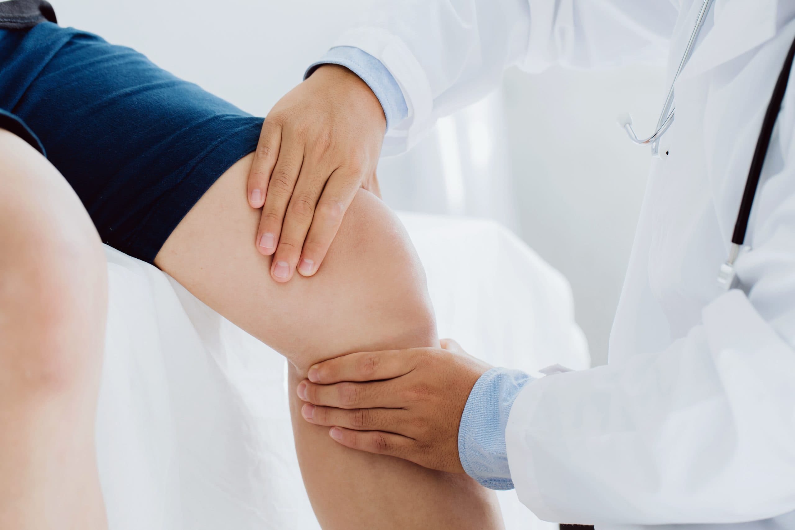Doctor examining knee in bright clinic setting