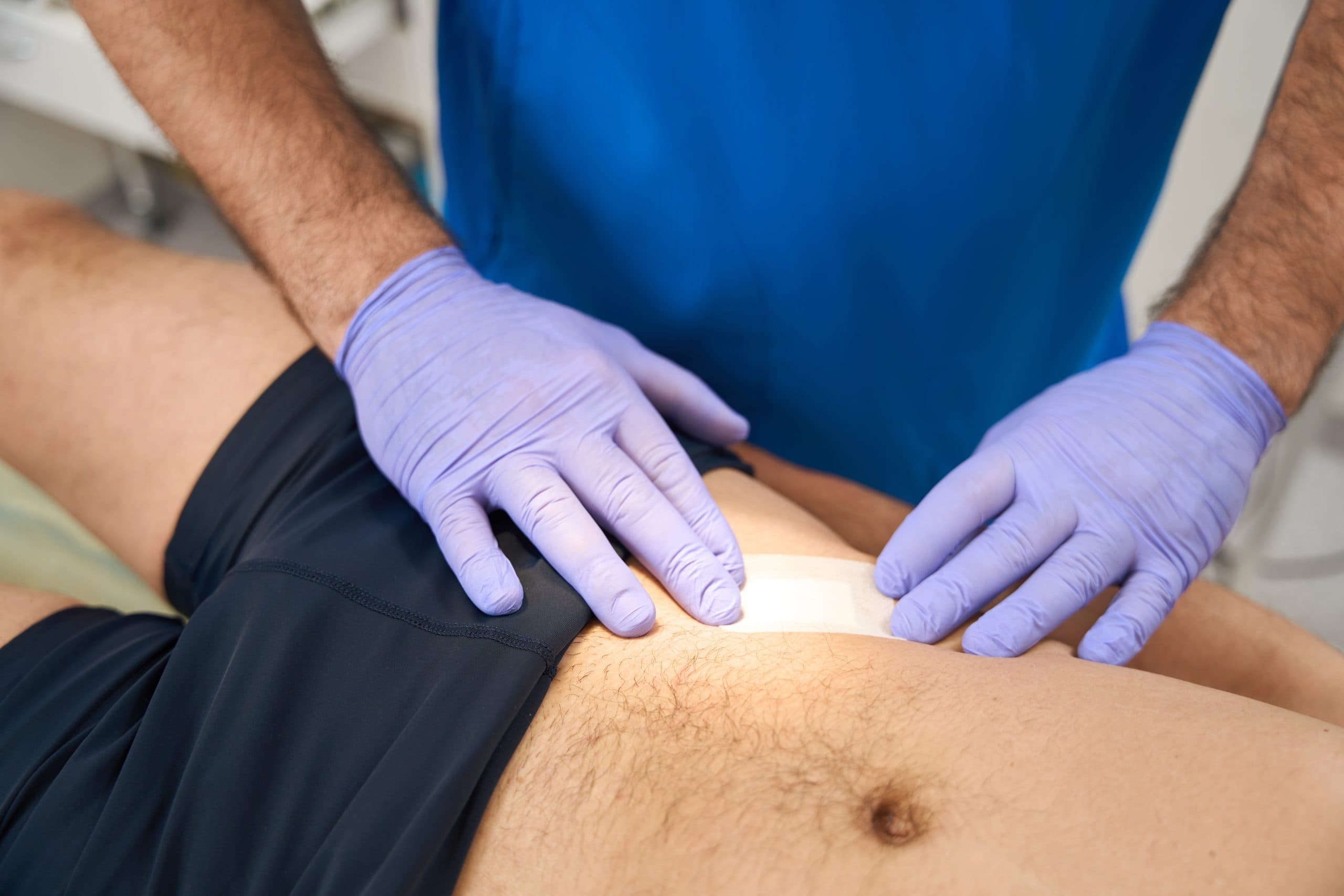 Purple-gloved clinician preparing lower-abdomen injection site