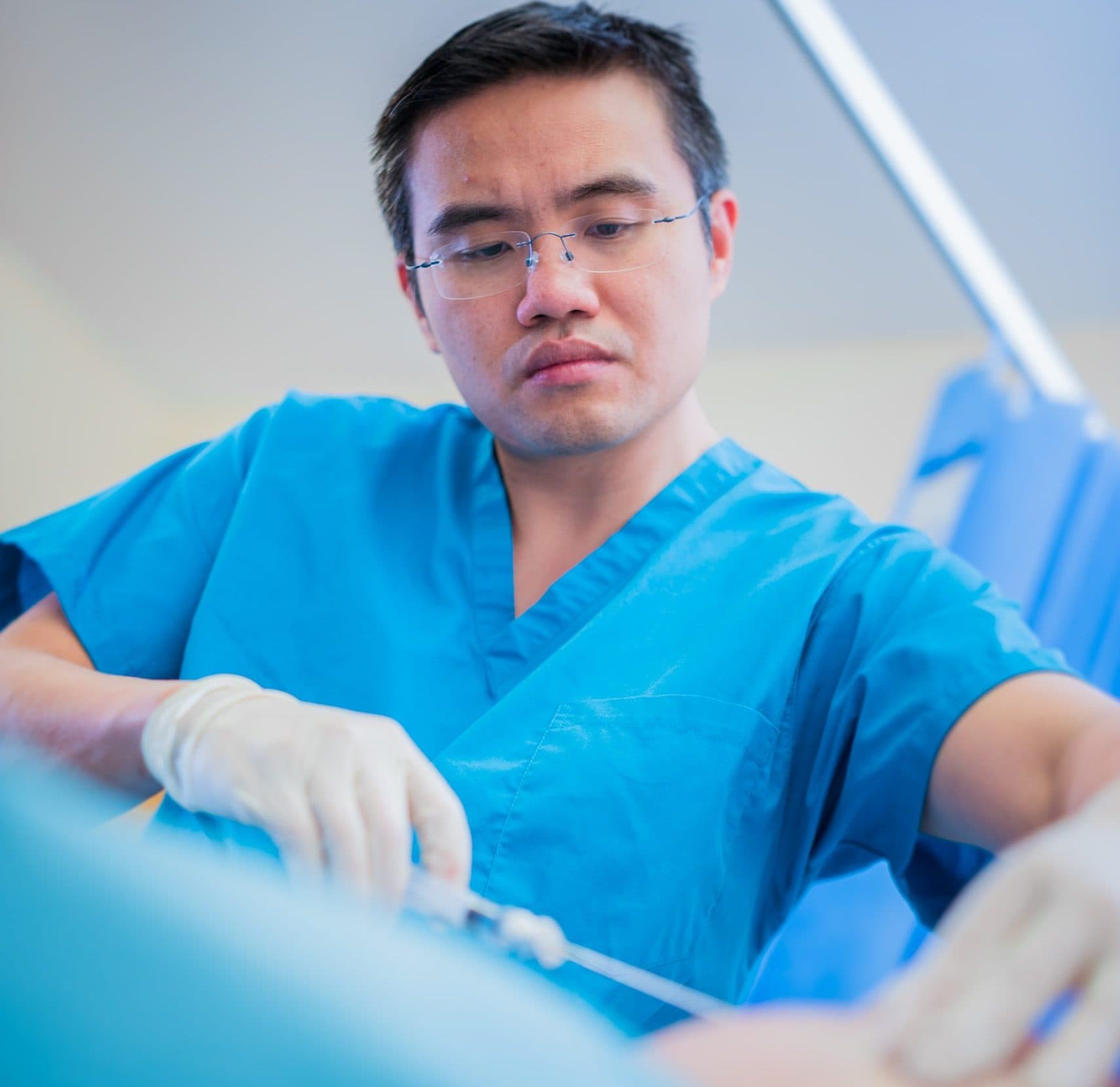 Surgeon in blue scrubs performing procedure