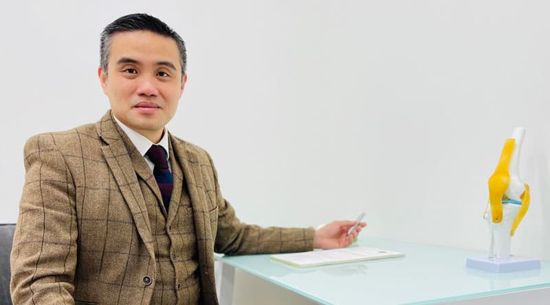 Professor in brown plaid suit discussing kneecap anatomy