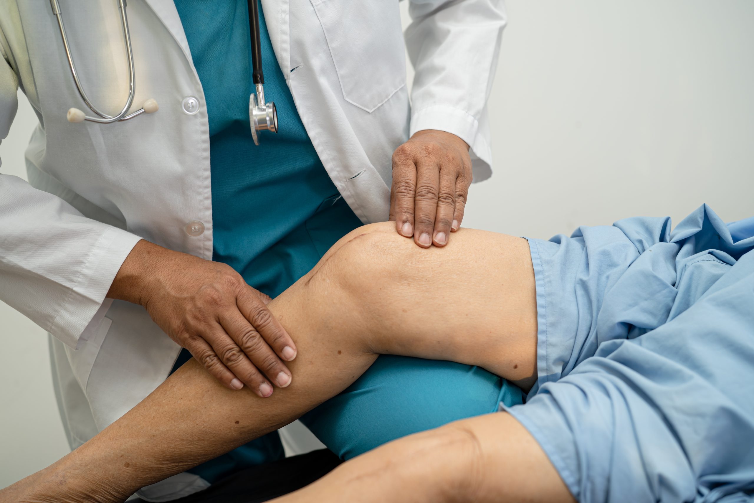 Asian,Doctor,Physiotherapist,Examining,,Massaging,And,Treatment,Knee,And,Leg